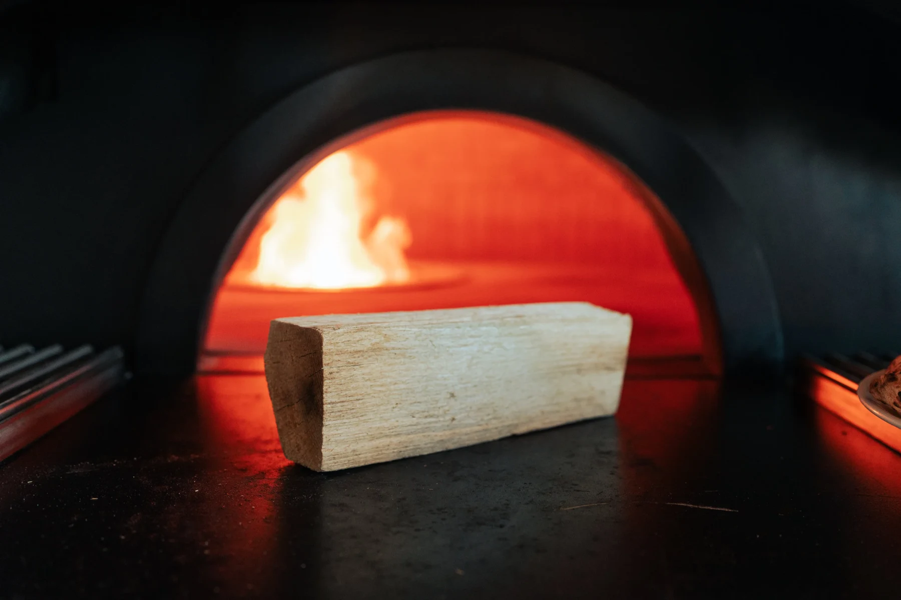 Fuego vivo bajo la bóveda de un horno de pizza